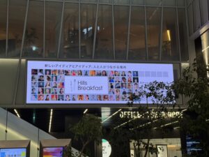 虎ノ門ヒルズのエントランスに設置された大型デジタルサイネージに、Hills Breakfastのイベント案内と多数の登壇者の写真が映し出されている様子。