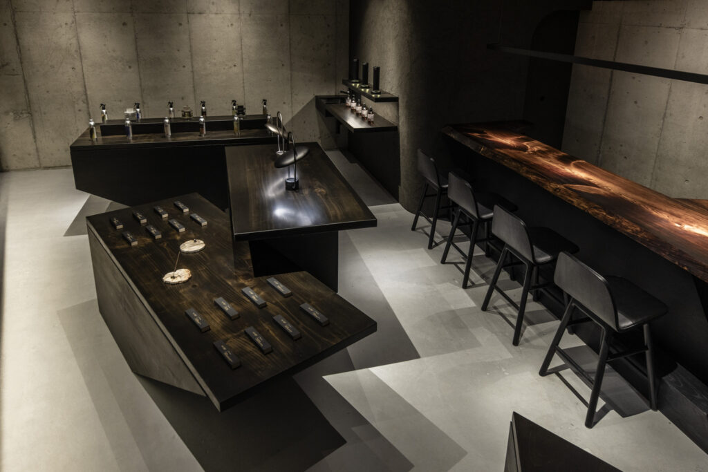 A quiet space framed by tabletops finished with fuki-urushi. Rows of candlelight, a solid-wood counter, and minimal furnishings define the interior of Lei’s flagship store.