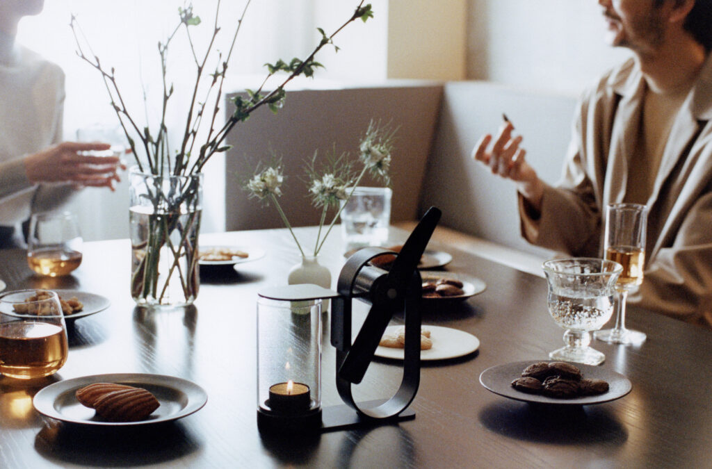 Two people talking at a dining table with desserts and drinks, with a Lei Non Electric Aroma Diffuser.