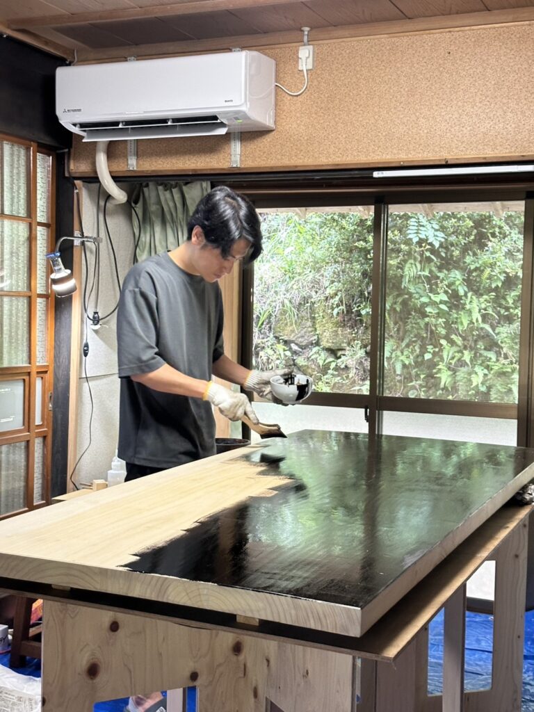Artisan applying urushi lacquer to a wooden Display Stand surface for Lei In Praise of Shadows Flagship Store in Yoyogi-Uehara, Tokyo.