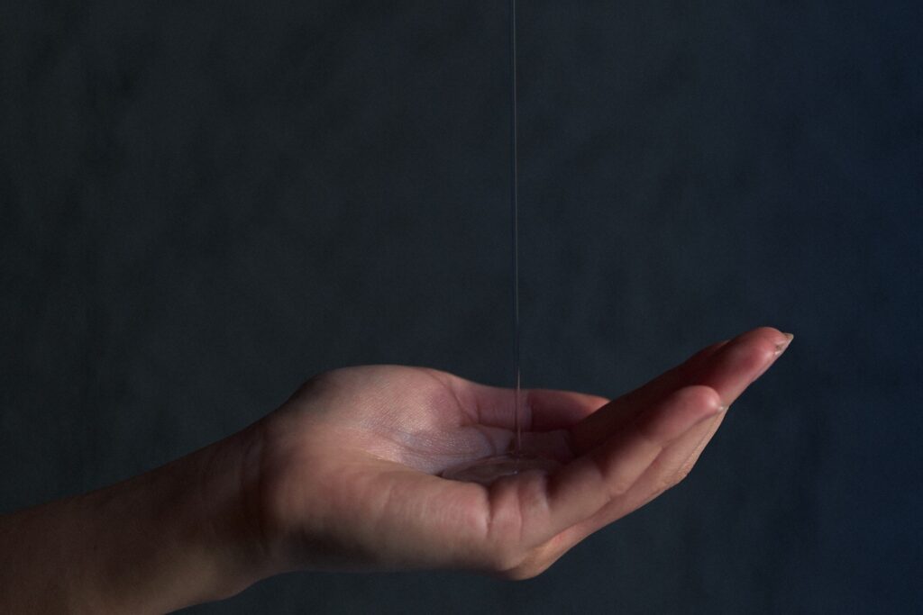 手のひらにKUONを垂らしている様子（暗い背景のクローズアップ）