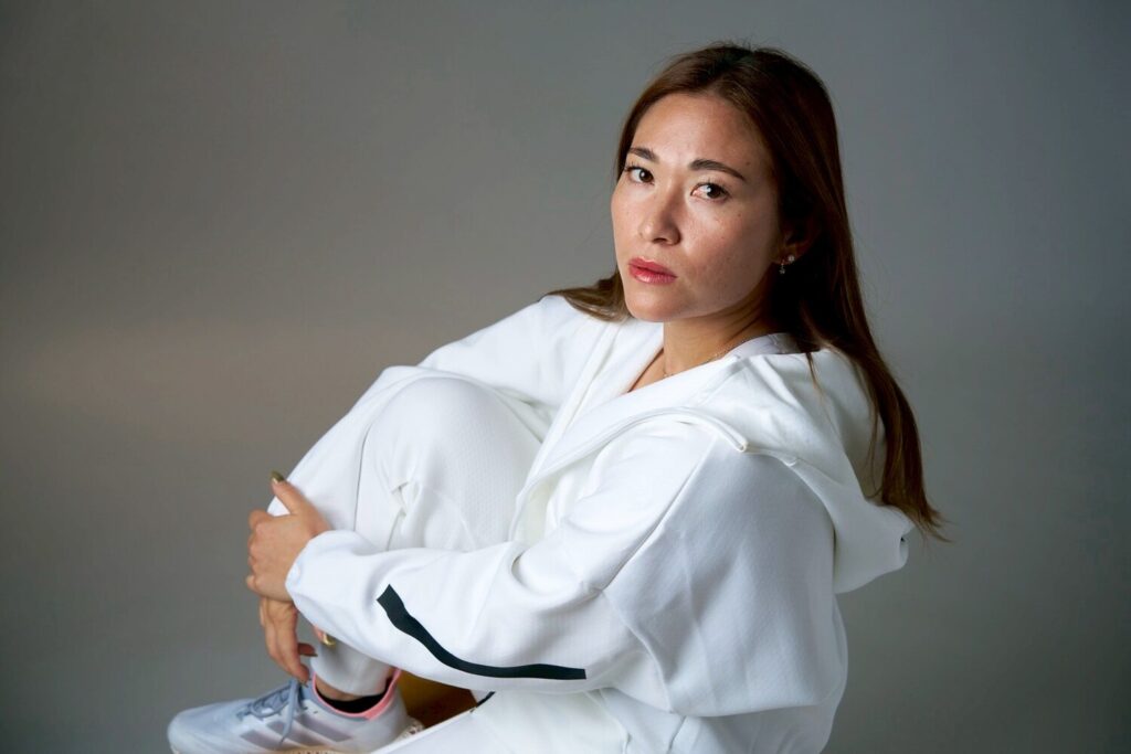 白いウェアで座り、静かな眼差しを向ける元フィールドホッケー日本代表・永井葉月さんのポートレート