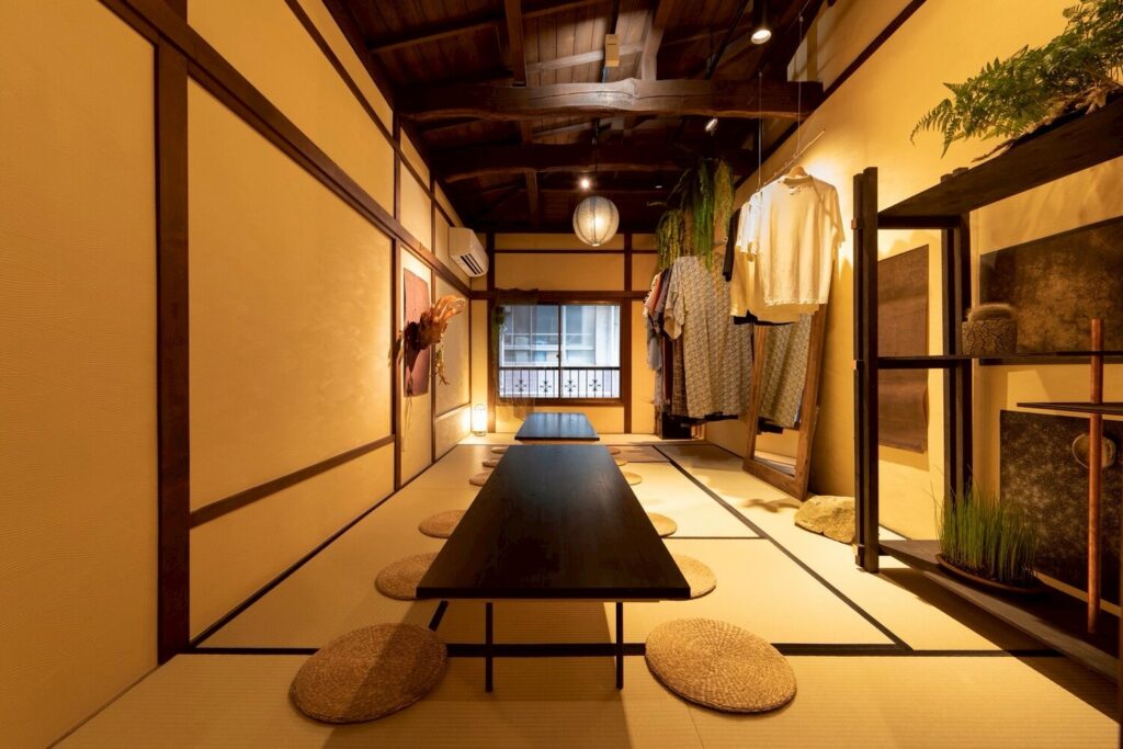 畳の店内に黒い座卓と円座が並び、奥に衣類のラックと温かな照明がある巧流-call-の空間