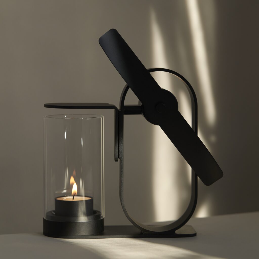 Lei Non-Electric Aroma Diffuser with a candle in a glass cylinder and a black metal frame, casting soft light and shadow.