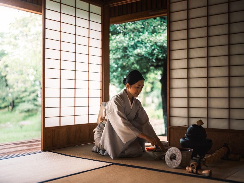 障子越しの光が差す和室で、茶道の所作として抹茶を点てる着物姿の神山ナオミさん