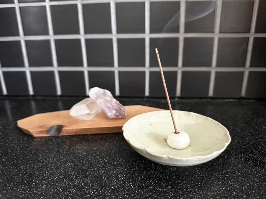 陶器の香皿に立てたお香と天然石。日常を整えるための静かな道具。