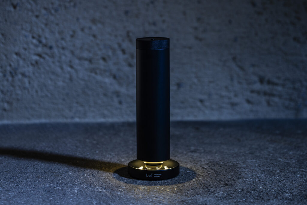 Lei professional diffuser in low light, a minimalist black cylindrical diffuser on an illuminated base.