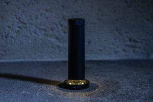 Lei professional diffuser in low light, a minimalist black cylindrical diffuser on an illuminated base.
