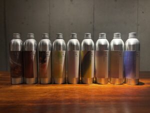 拭き漆加工を施したカウンターに並ぶLeiのアルミボトル9本（KUON、Fig Royale、Honey Amber、Green Symphony、White Tea、Citrus Wood、Spicy Jasmine、Cashmere Musk、Sea breeze Oud）