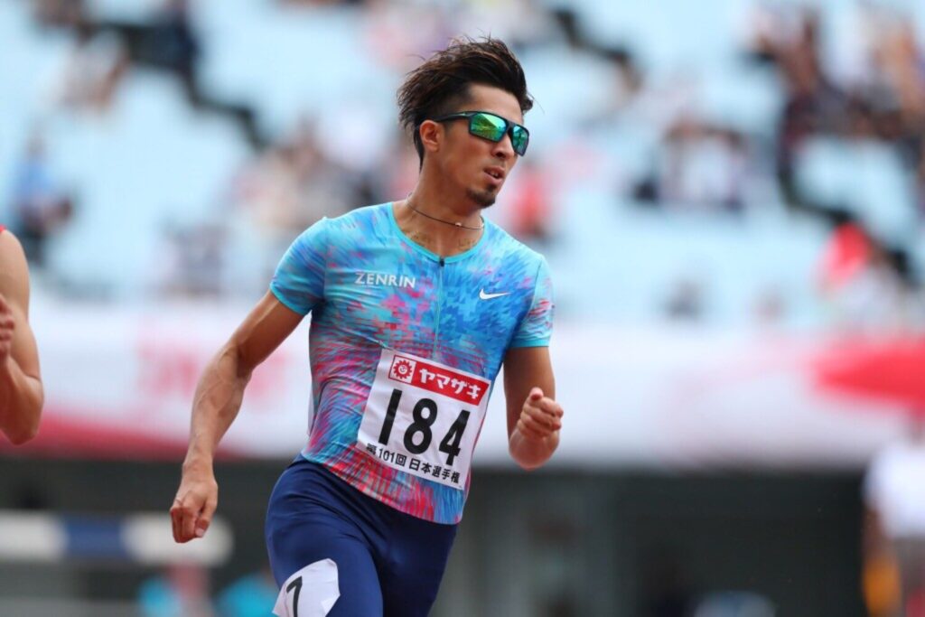 レース中の藤光謙司さん。サングラスを着用し、陸上トラックを走っている。