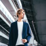 高架下でジャケット姿の藤光謙司さんが立ち、遠くを見つめているポートレート。