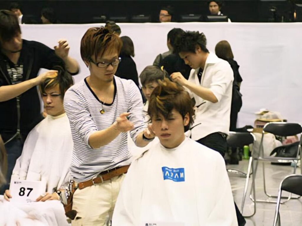 ヘアコンテスト会場で、竹内稔さんが男性モデルの髪をスタイリングしている様子