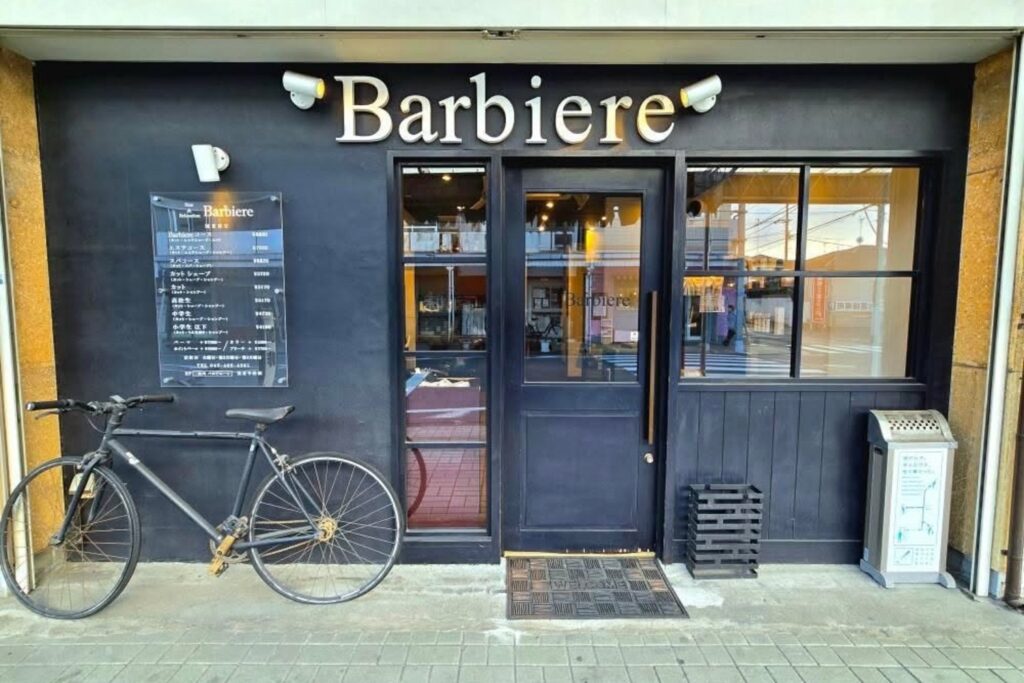 男性専用ヘアサロン「Barbiere」外観（黒いファサードと店名サイン、入口前の自転車）