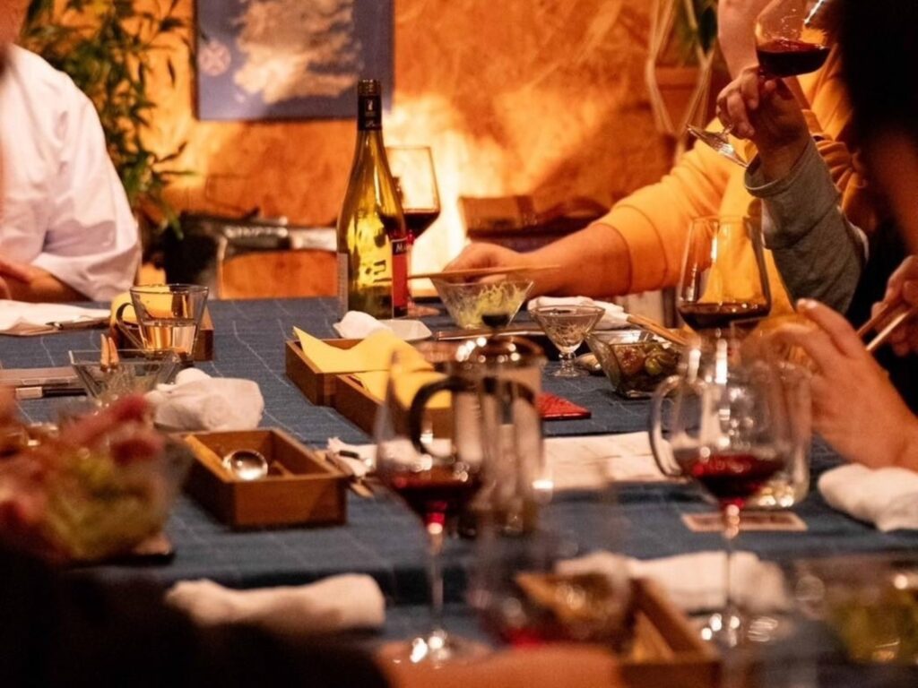 trattoria filoの食卓風景。ワインと料理が並ぶテーブルを囲み、会話と食事を楽しむ様子。