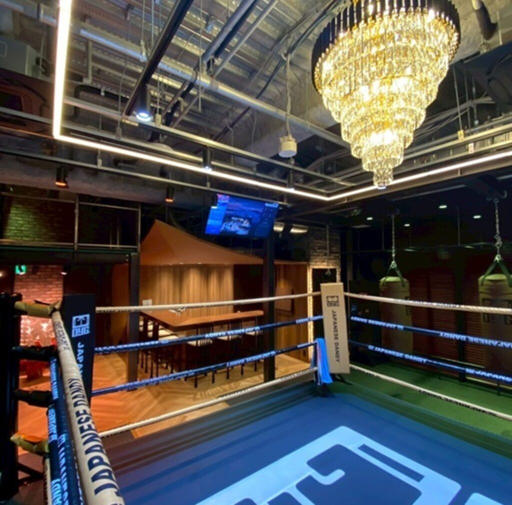 Interior of OYG Ginza, a members-only boxing and training space with a boxing ring and chandelier lighting.