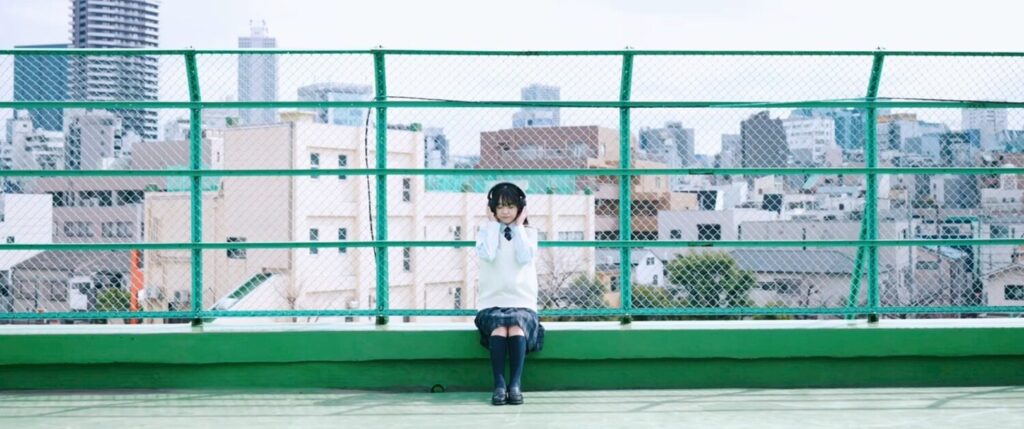 hayatoさんの映像作品ビジュアル。屋上でヘッドホンをつけた制服姿の人物が座るシーン