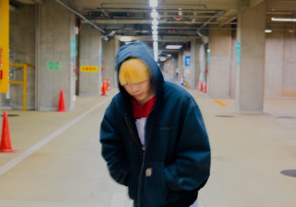 映画監督・映像作家 hayatoさんのプロフィール写真。地下通路のような空間でフードをかぶり、こちらに向かって歩く姿
