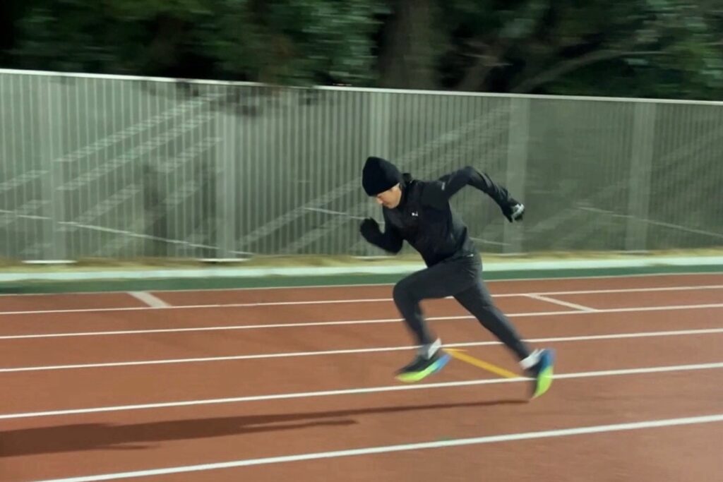 夜の陸上競技場で走る元陸上短距離走日本代表の小林雄一さん