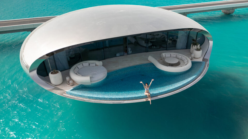 海上に浮かぶ近未来的なヴィラのプールサイドで、両手を広げるSUMMYさん