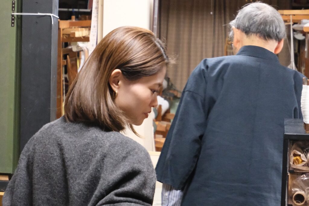工房で、職人のそばに立ちながら静かに視線を向ける藤井由香里さん
