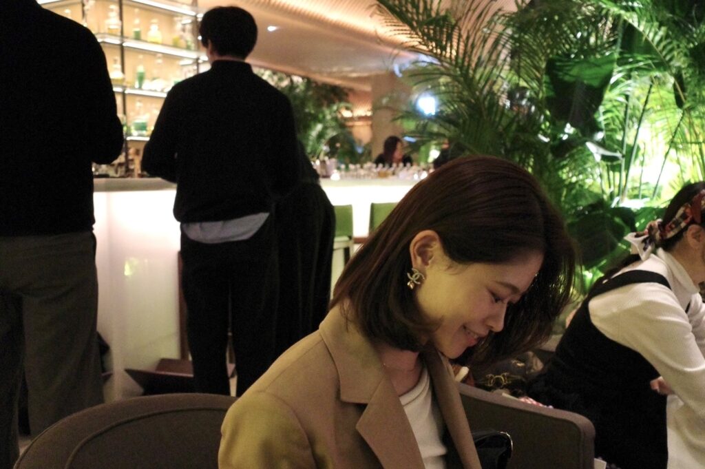 グリーンに囲まれた夜のラウンジで、やわらかな表情を見せる藤井由香里さん