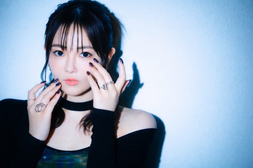 黒の衣装をまとい、指先を顔に添えてポーズを取る篠原彩加さんのポートレート