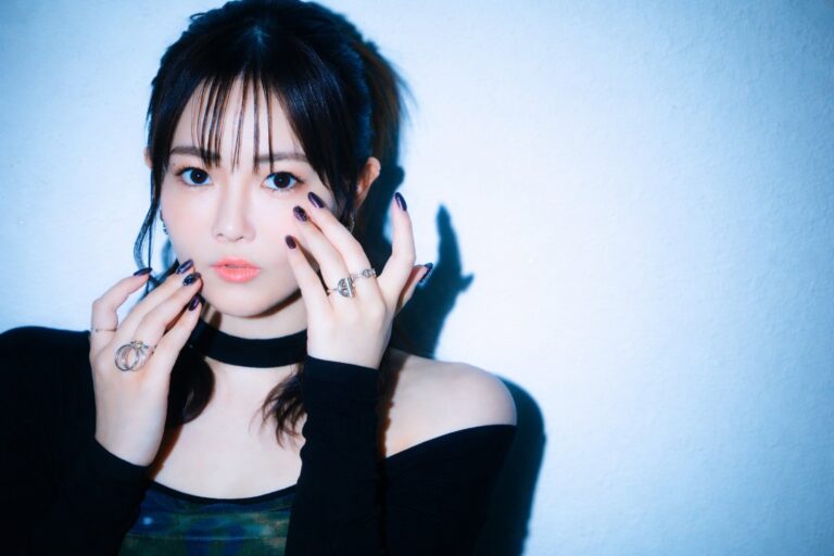 黒の衣装をまとい、指先を顔に添えてポーズを取る篠原彩加さんのポートレート
