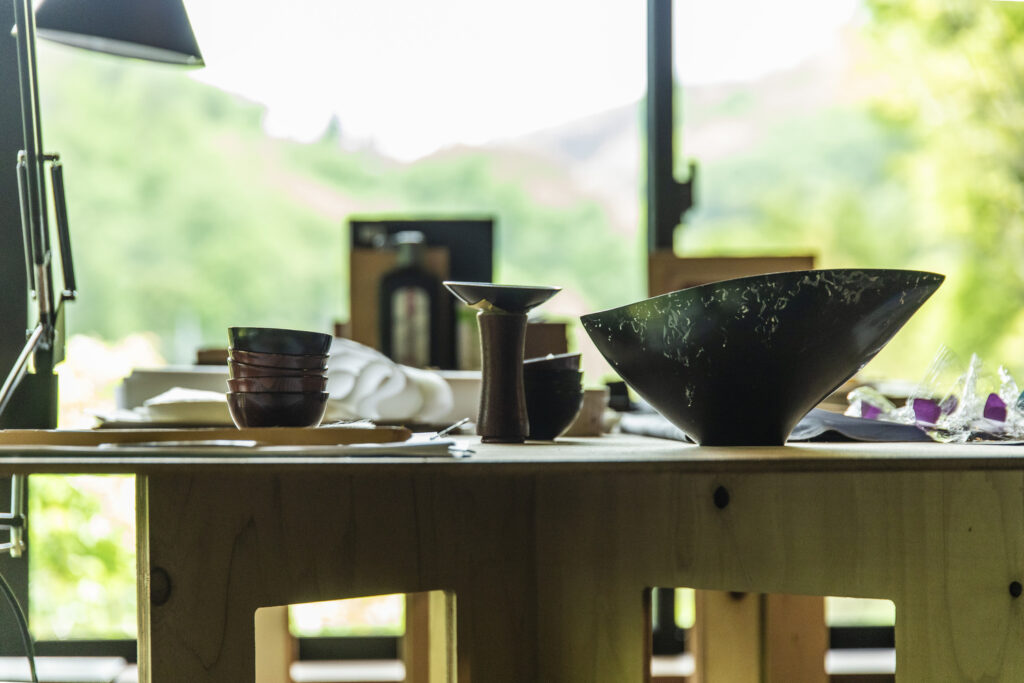 工房の窓辺に並ぶ漆の器と作品。やわらかな自然光の中で黒の器が静かに佇む様子