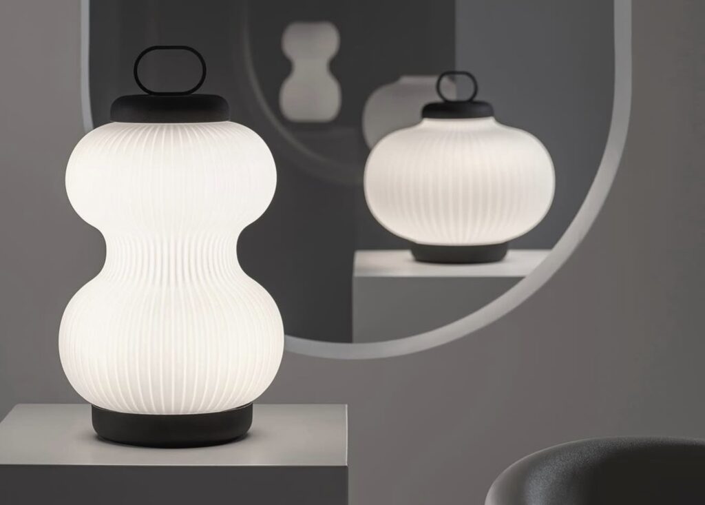 Lampade in vetro opalino con superficie scanalata, illuminate e disposte in uno spazio minimale