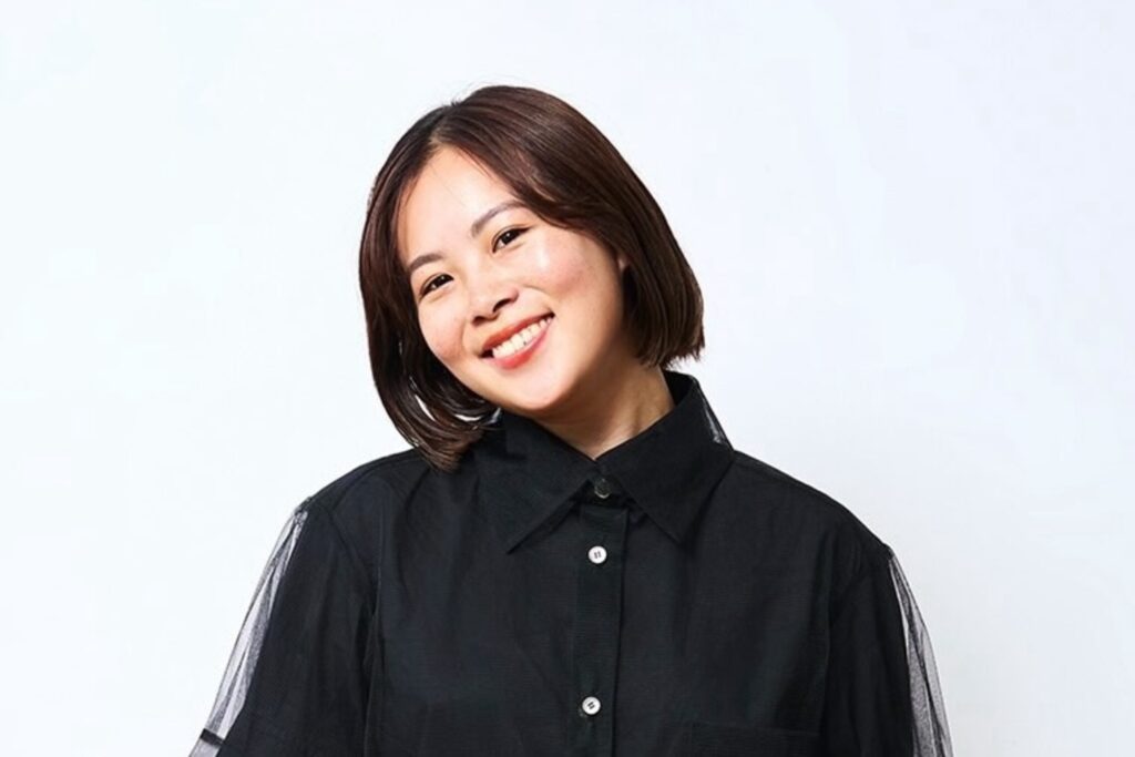 株式会社EmpaC代表取締役・松山真衣さんのポートレート。黒いシャツを着て、白い背景の前で微笑んでいる。