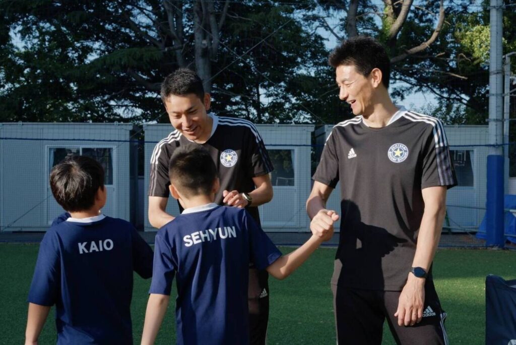 サッカースクールで子どもたちと握手を交わす安英学さん