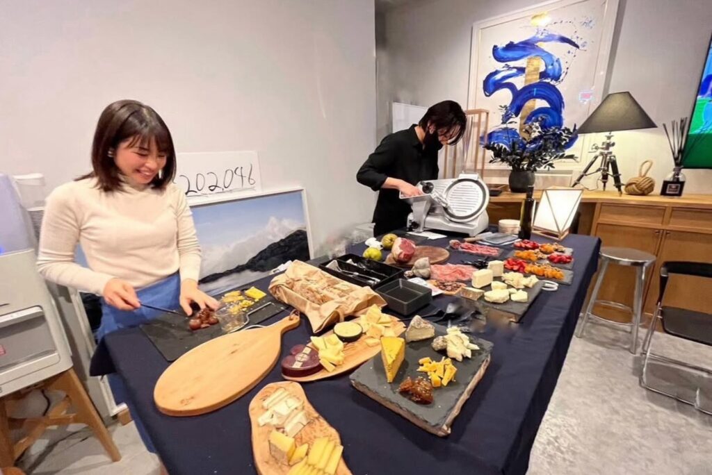 チーズや食材を並べたテーブルの前で、準備をするオーガニックインポーターの真衣さん