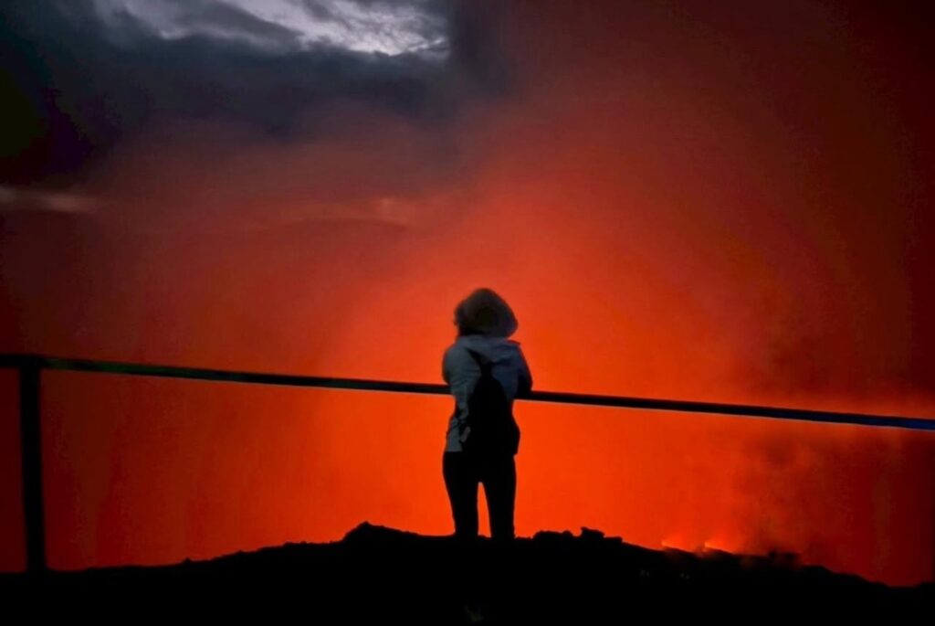 赤く染まる火山の光を前に立つ真衣さんの後ろ姿