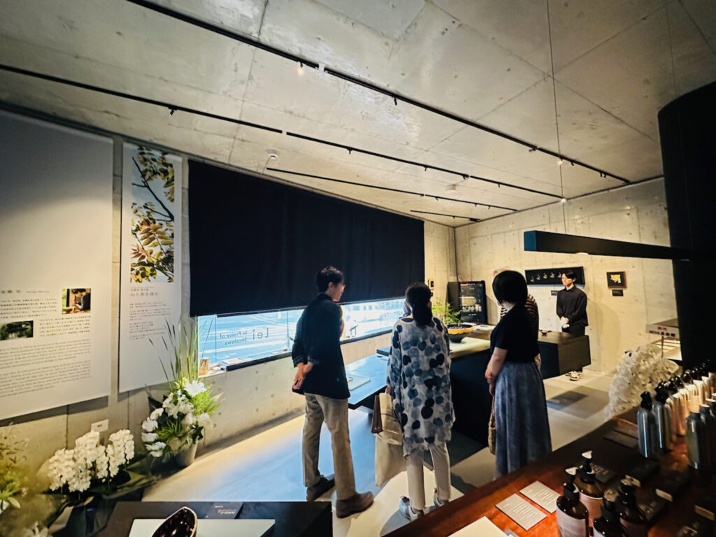 Lei Gallery Tokyo (Lei In Praise of Shadows Flagship Store) で、来場者が漆芸家 室瀬祐さんの漆芸作品について説明を受けている様子。