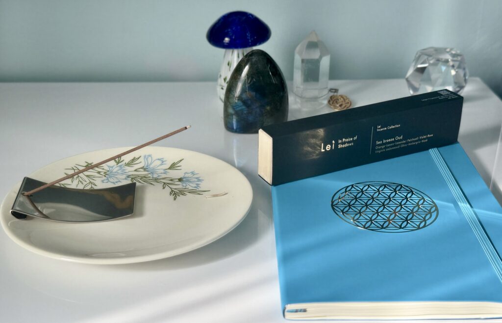 Lei Incense Collection Sea breeze Oud with an incense stick, ceramic plate, and objects arranged on a white surface.