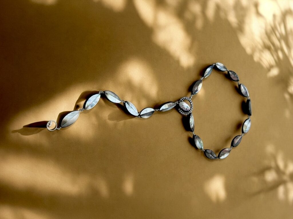 Iridescent necklace by Simon Alcantara photographed in warm light and shadow.