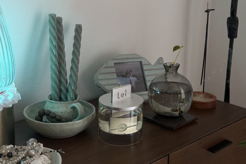 Lei card diffuser nella camera da letto di Adelaide Mati, accanto a un vaso e alcune candele