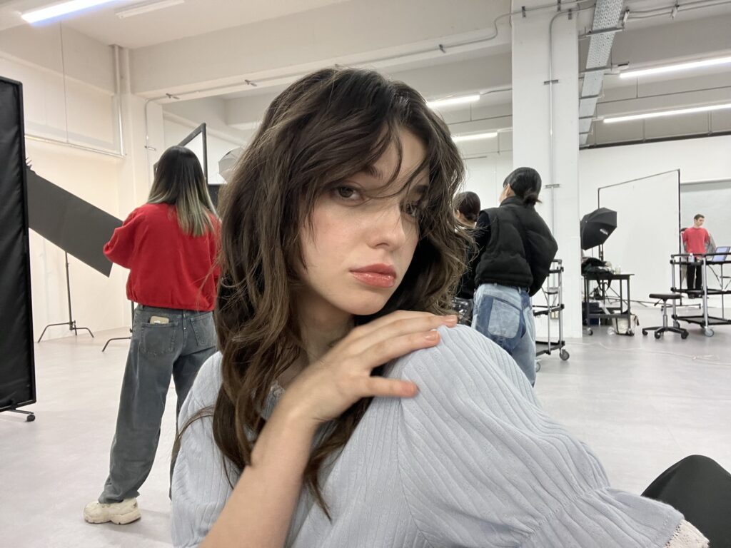Adelaide Mati seduta in uno studio fotografico, con lo staff al lavoro sullo sfondo